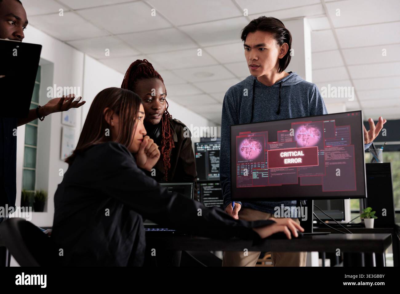 Diverse group of software developers having hacked server and security breach alert on computer display trying to solve hacking problem. Encountering critical error message flashing on screen. Stock Photo