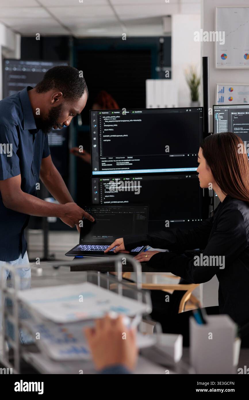 Diverse team of app developers talking about programming in software company office. Artificial intelligence cloud programers compiling code on terminal window server, doing teamwork Stock Photo