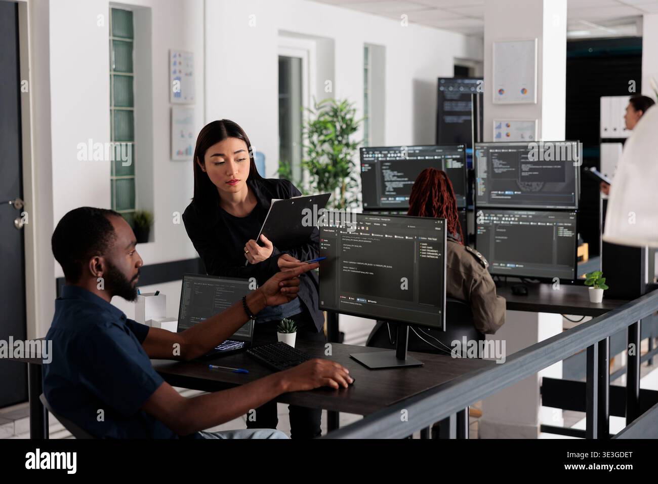 African american web developer using computer to write code and develop algorithm program in big data office room. System engineers working on user interface with html script and terminal window. Stock Photo