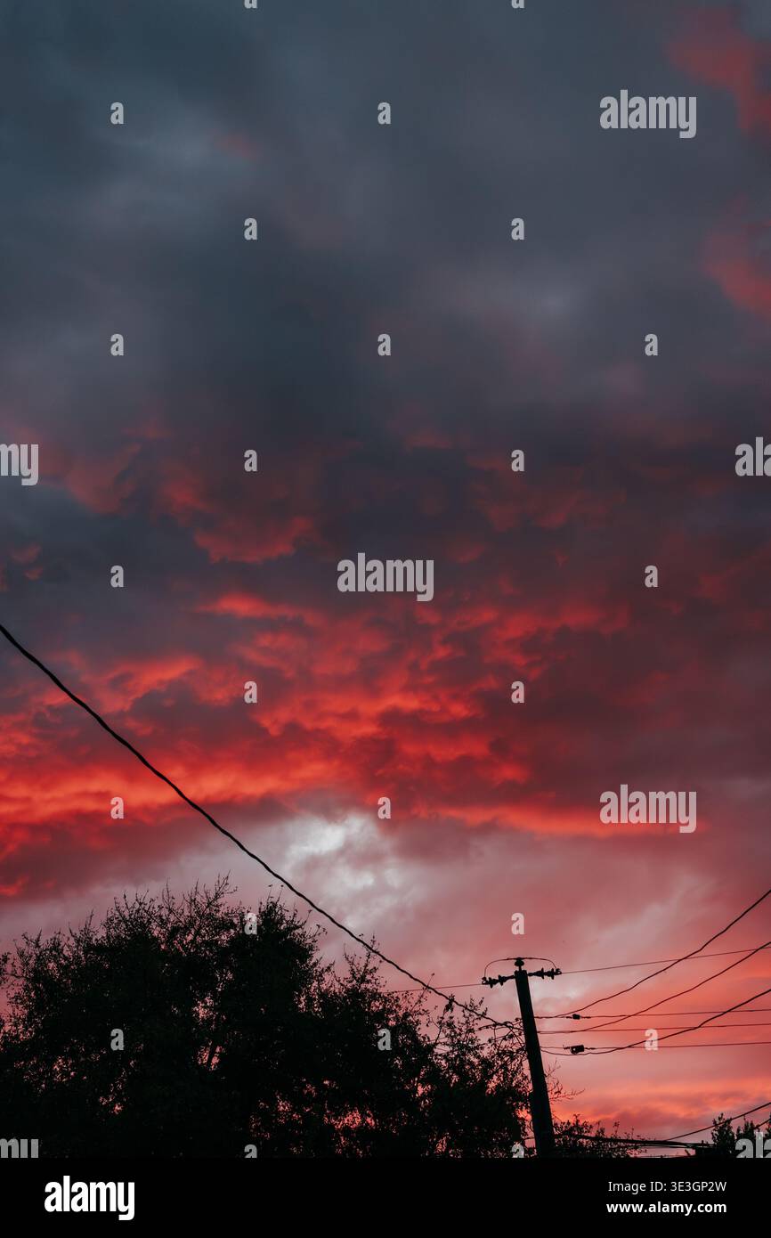 Power lines against dramatic sunset on a fall evening in October Stock Photo