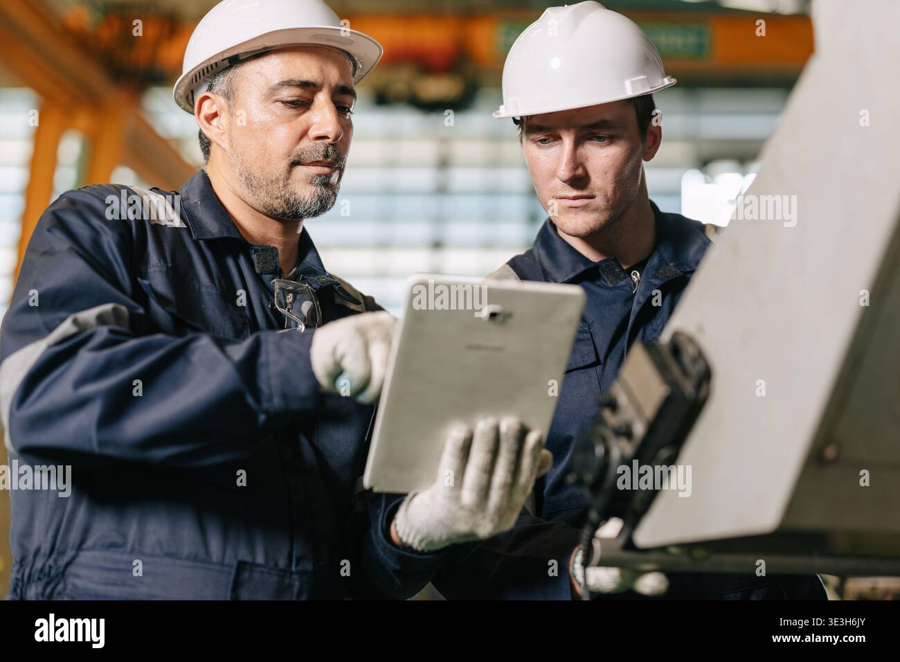 Senior engineer team work with young worker help together checking control operate machine with tablet computer technology Stock Photo