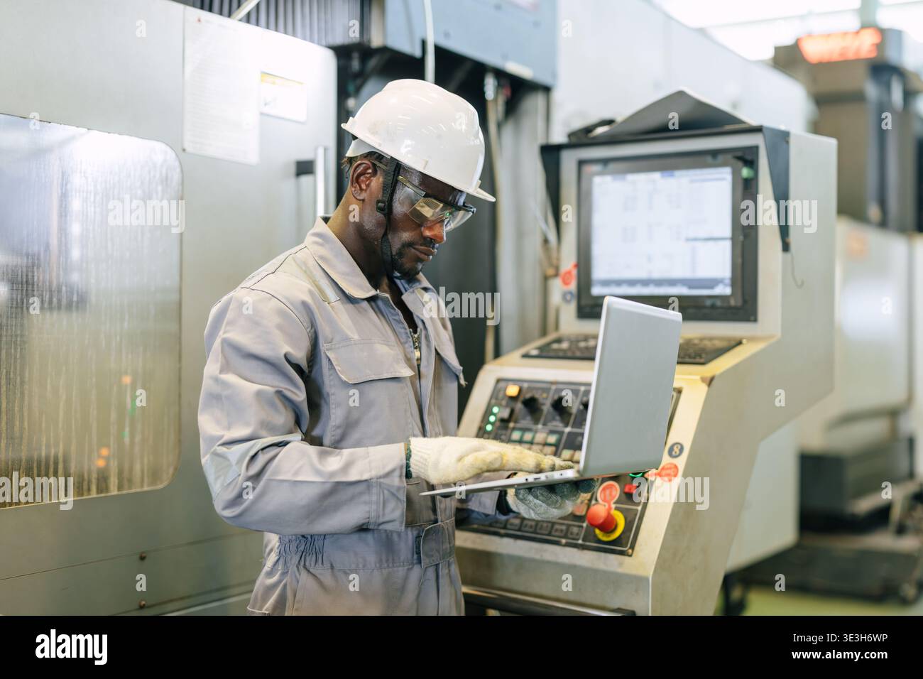 Professional African black worker, Engineer male working control operate CNC metal milling machine in industry factory with laptop computer. Stock Photo