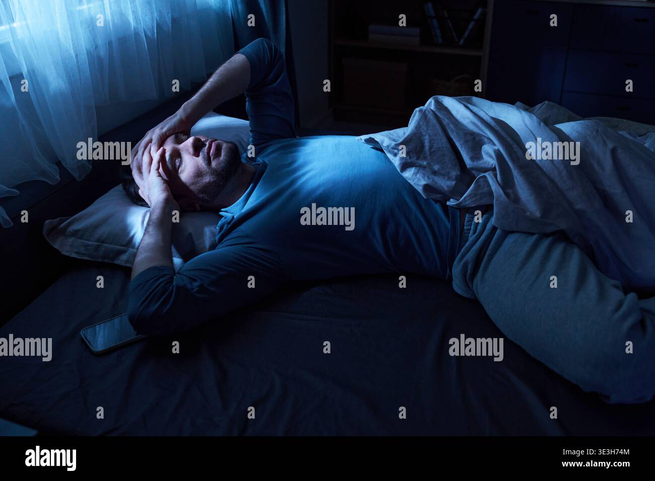 Adult Man Lying in Bed Suffering from Insomnia at Night Stock Photo