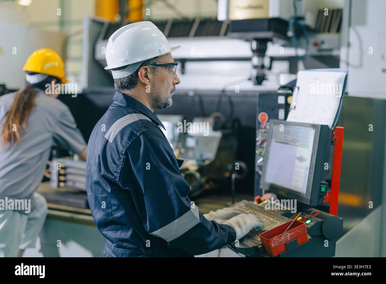 CNC Lathe Machine Engineer Operator Worker Working Entering Work Batch Production Program Data at Heavy Metal Factory Stock Photo