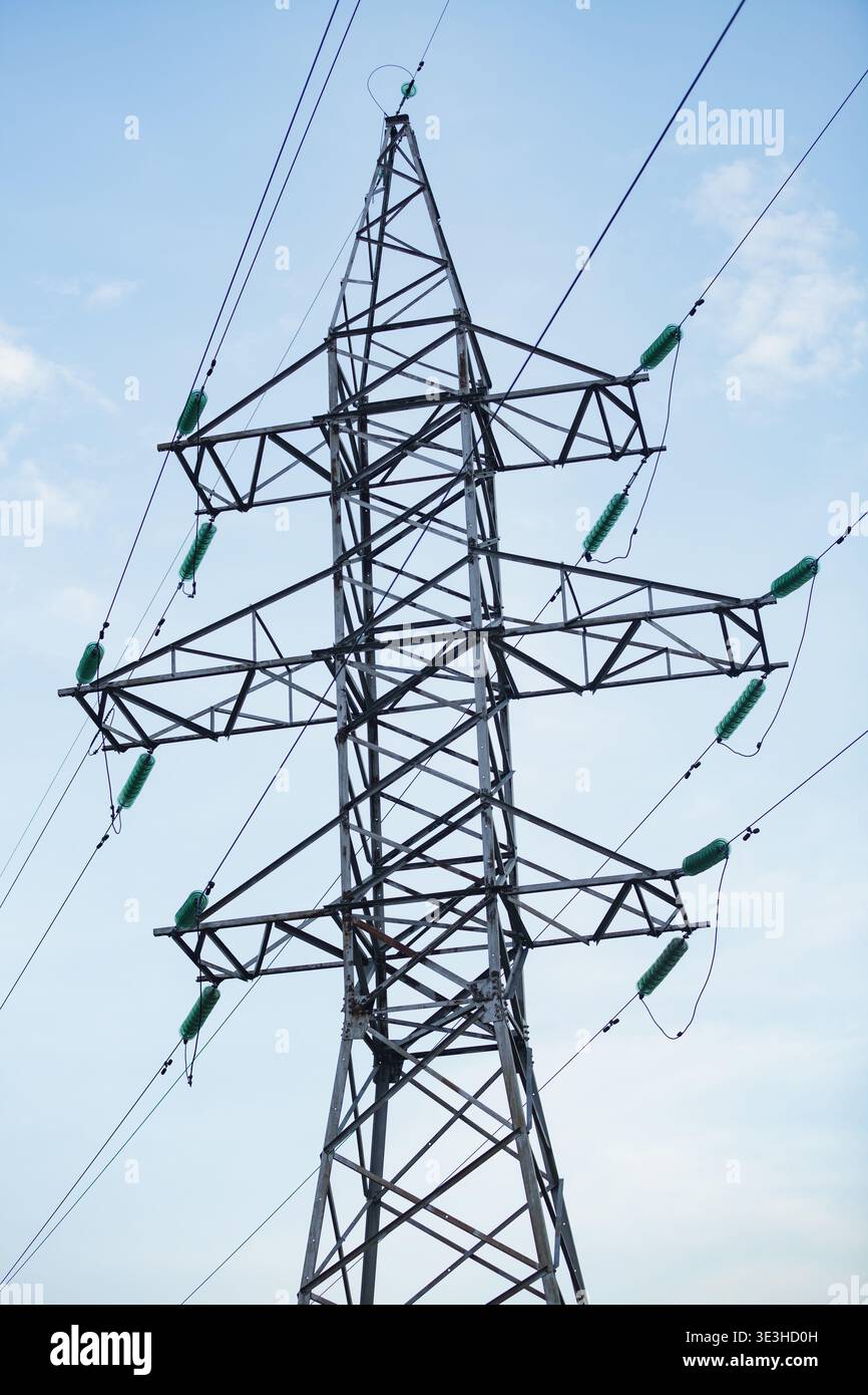 High voltage power line pylon with glass insulators against a blue ...