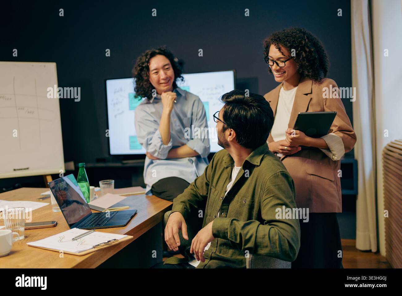 collaborative project troubleshooting session, team members analyze charts and code together friendly Stock Photo