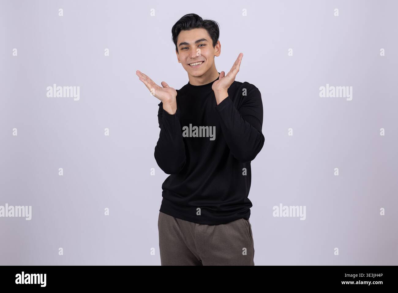 Cheerful young man posing with hands on his face in studio Stock Photo