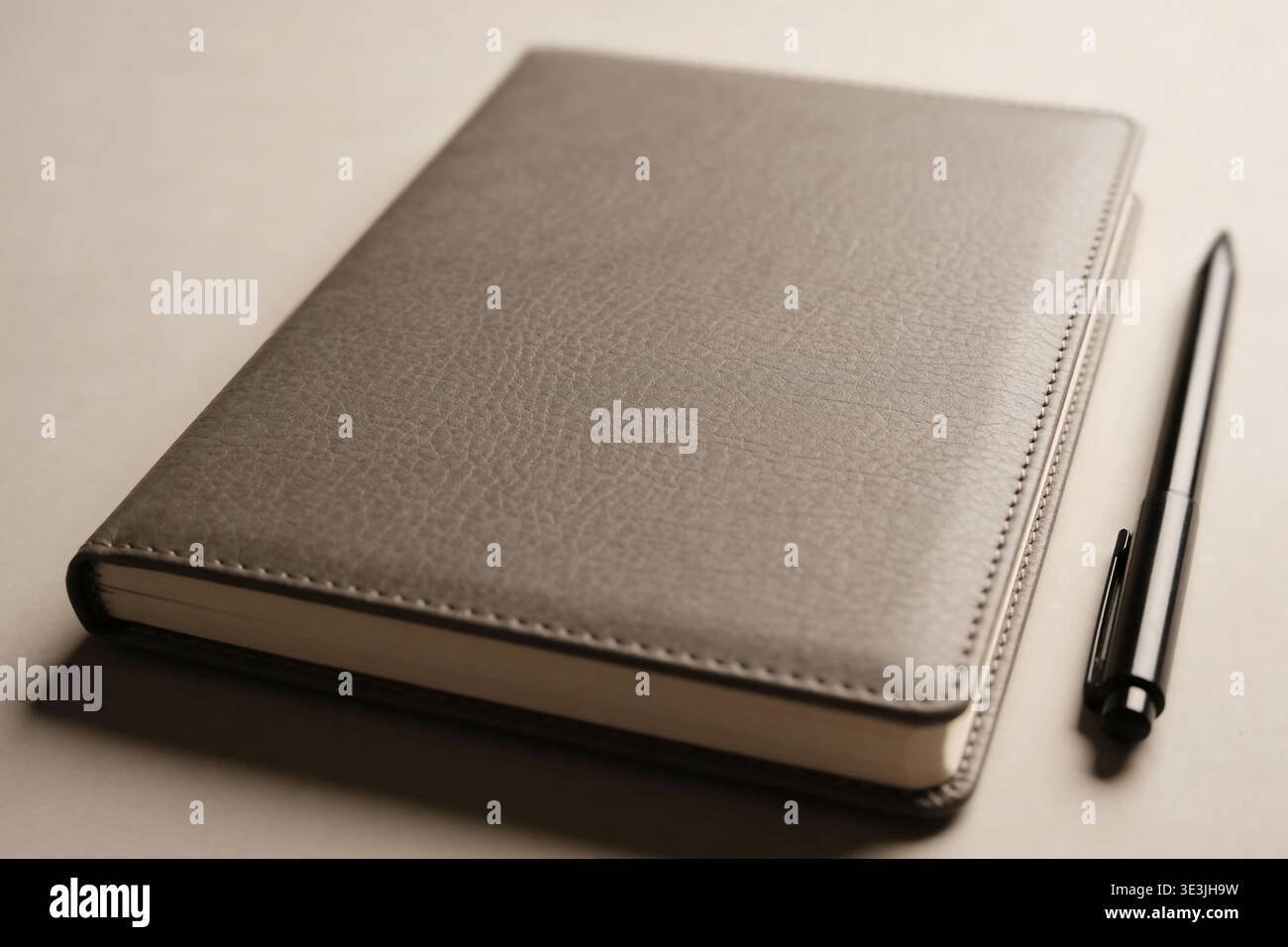 A close-up view of a sophisticated gray journal with a textured cover, placed next to a modern black pen, suggesting organization and planning Stock Photo