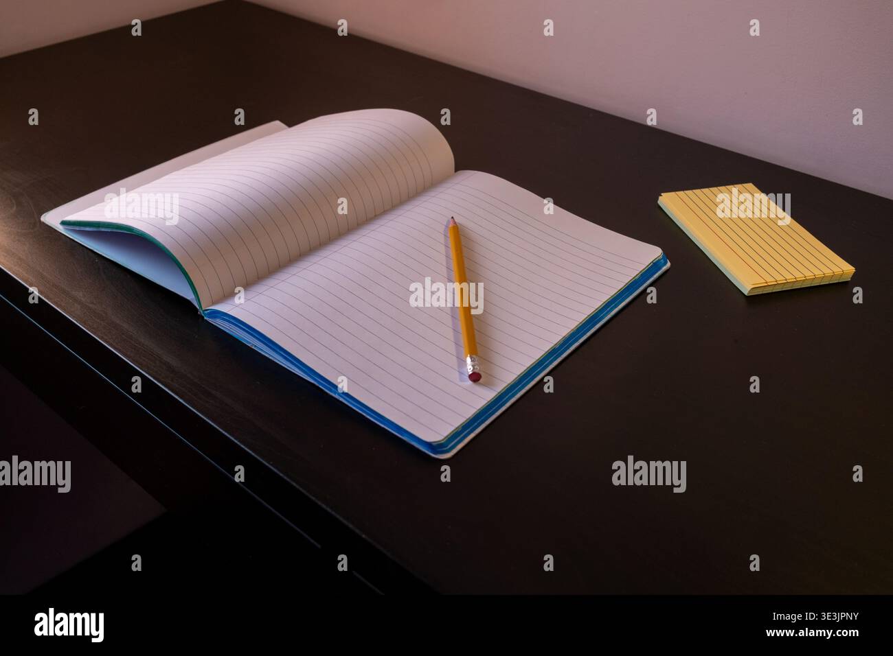 Open notebook with pencil on dark table Stock Photo
