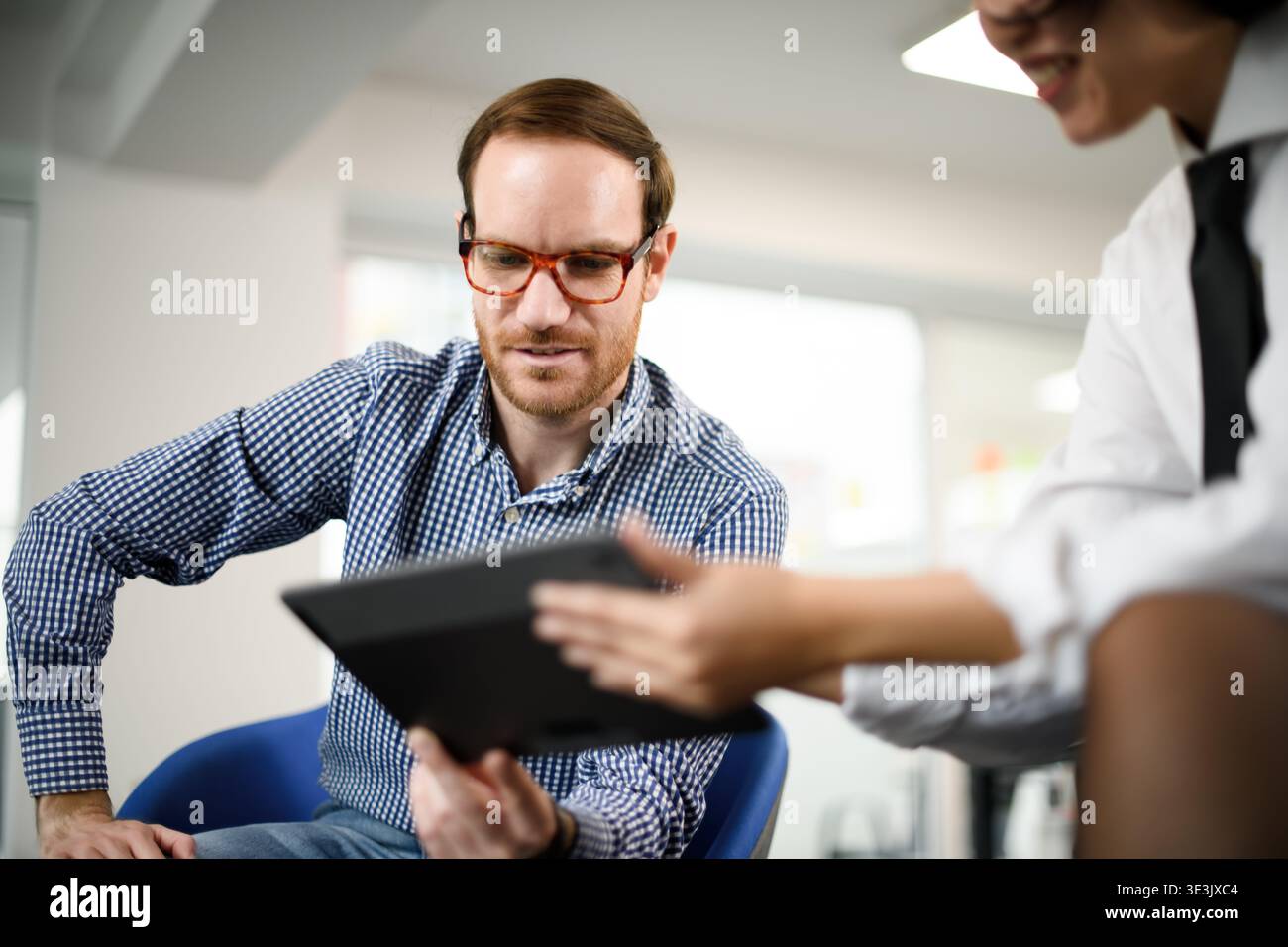 Business professionals discussing strategies during a meeting in a modern office space with a focus on digital tools and technology Stock Photo