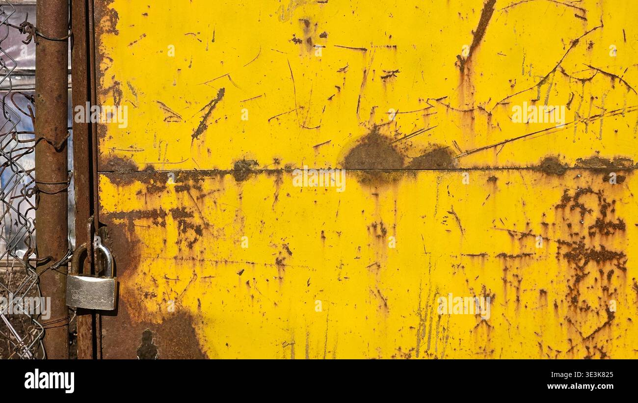 Rusty yellow metal gate with padlock and scratched industrial surface - Smartphone Captured Stock Image
