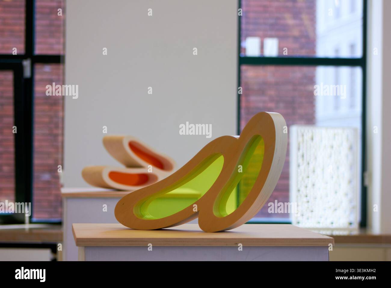 Two abstract contemporary sculptures displayed on white pedestals in a bright gallery space with large windows. The foreground sculpture features a Stock Photo