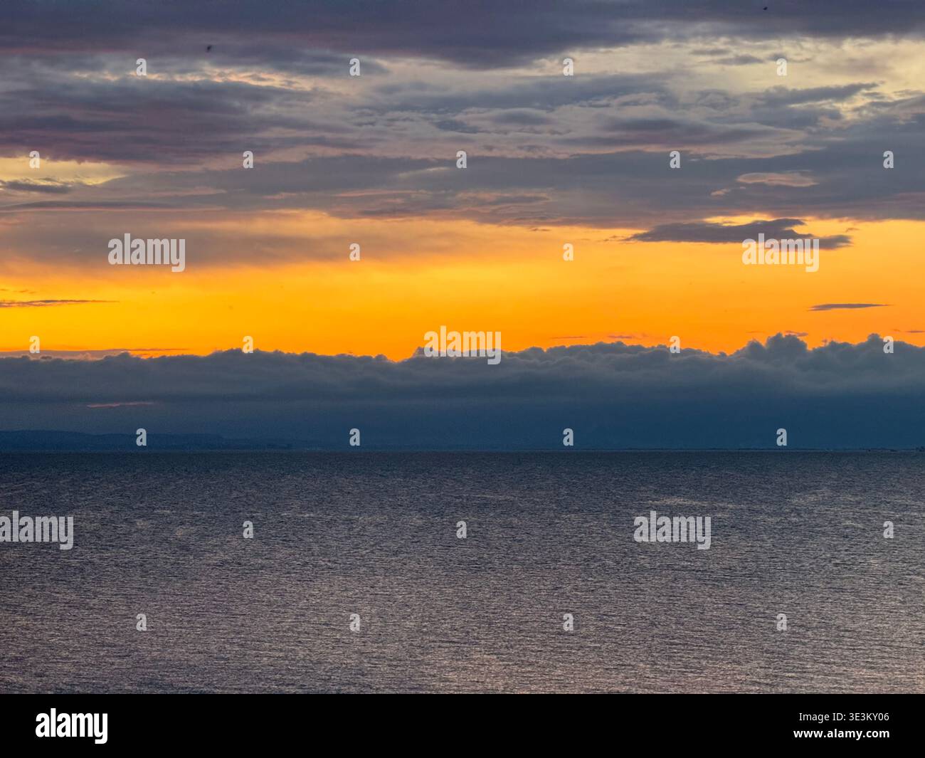 Dramatic red sunset over Lake Constance (Bodensee) with glowing clouds and calm water, tranquil evening seascape in Central Europe. - Smartphone Captured Stock Image