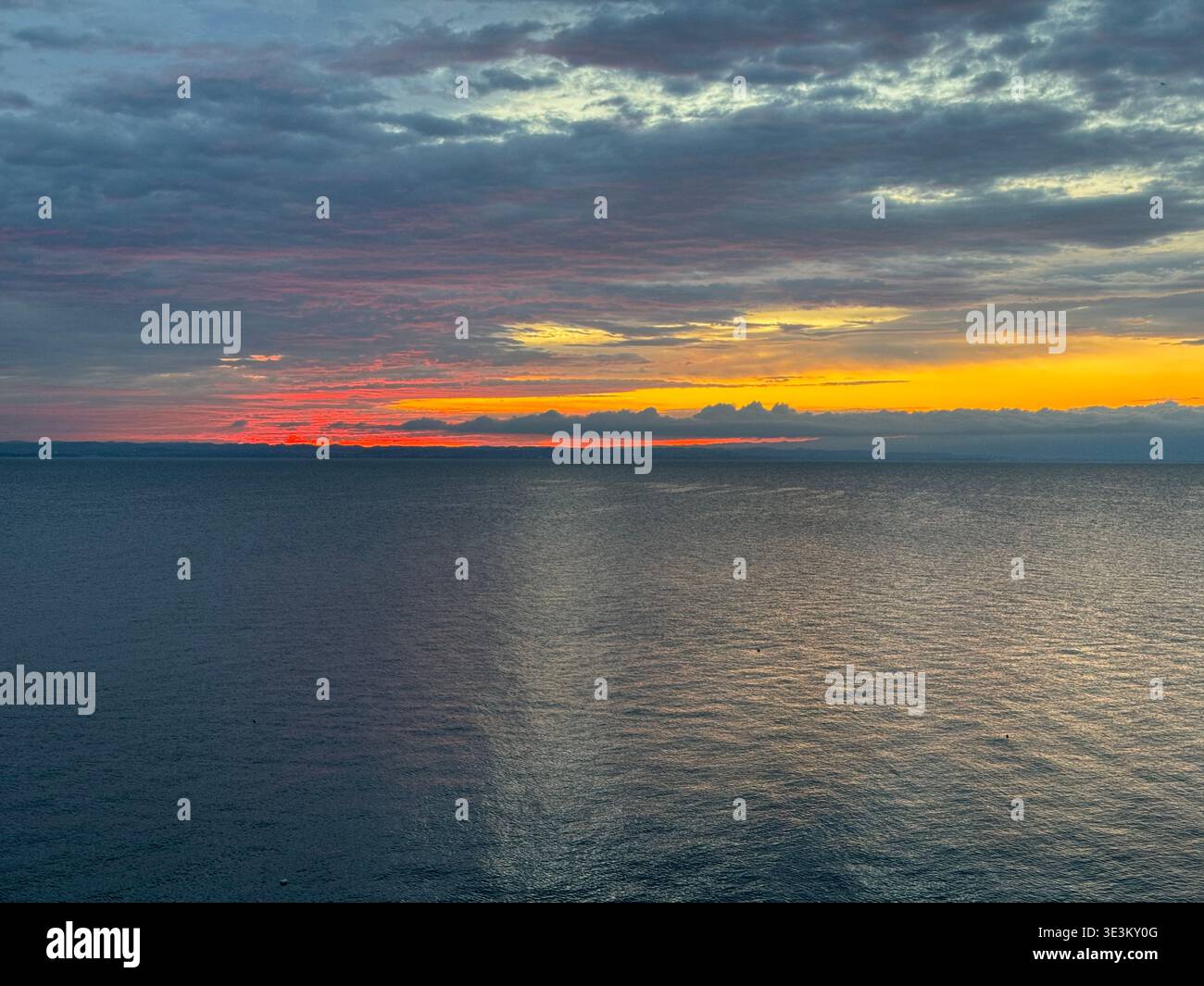 Dramatic red sunset over Lake Constance (Bodensee) with glowing clouds and calm water, tranquil evening seascape in Central Europe. - Smartphone Captured Stock Image