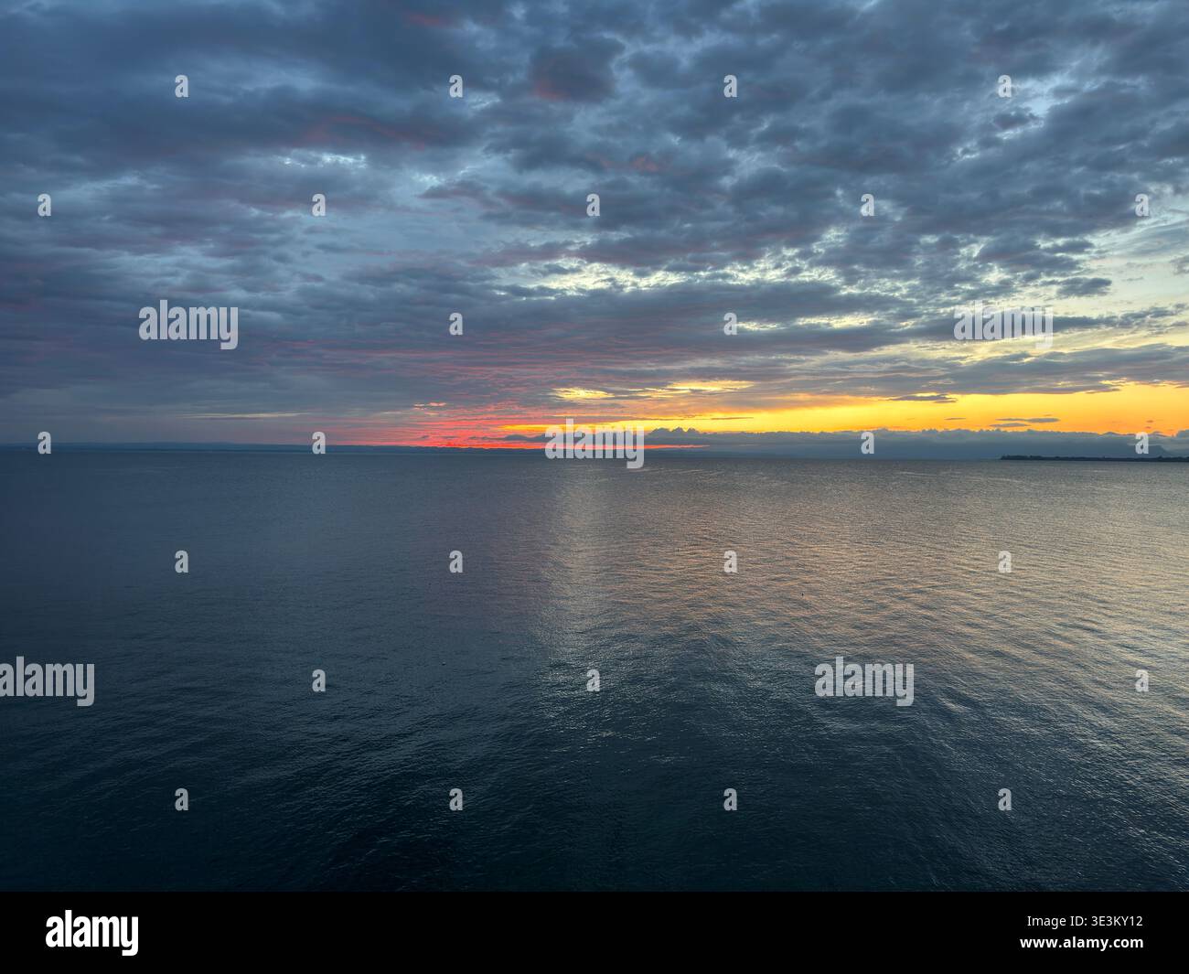 Dramatic red sunset over Lake Constance (Bodensee) with glowing clouds and calm water, tranquil evening seascape in Central Europe. - Smartphone Captured Stock Image