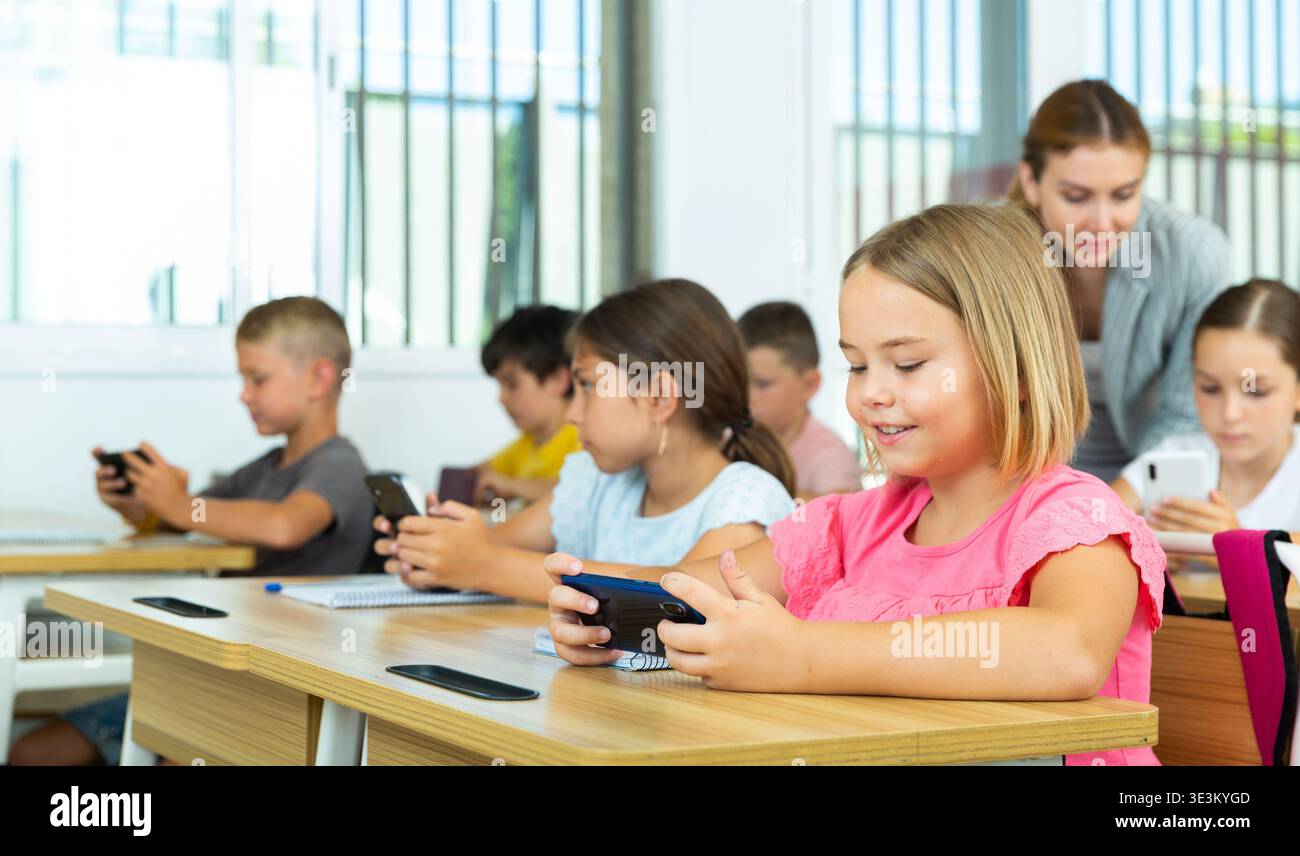 Pupils using mobile phones during lesson in school Stock Photo