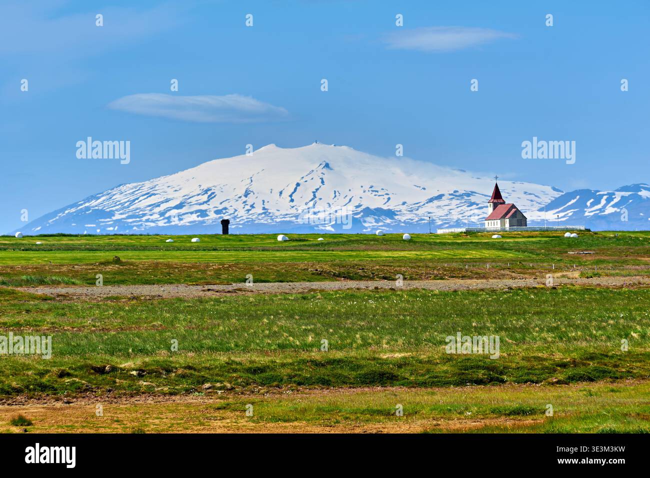 Stadarstadur Church stands alone with a snowy mountain in the background on a sunny day, showing the beauty of Iceland's landscape. Stock Photo
