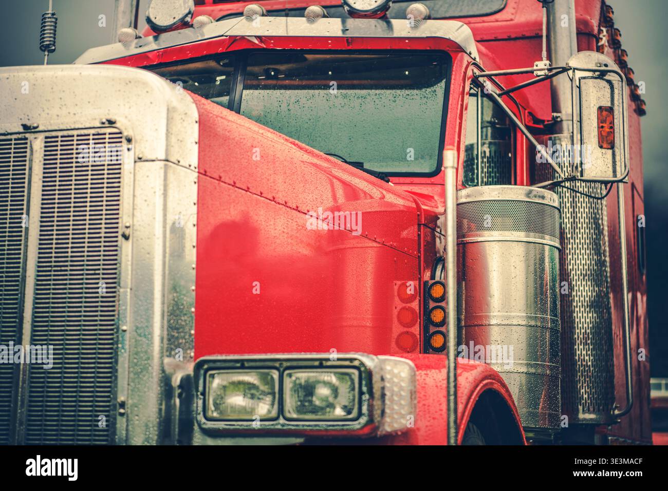 A red truck stands in the rain with water droplets on its surface. Stock Photo