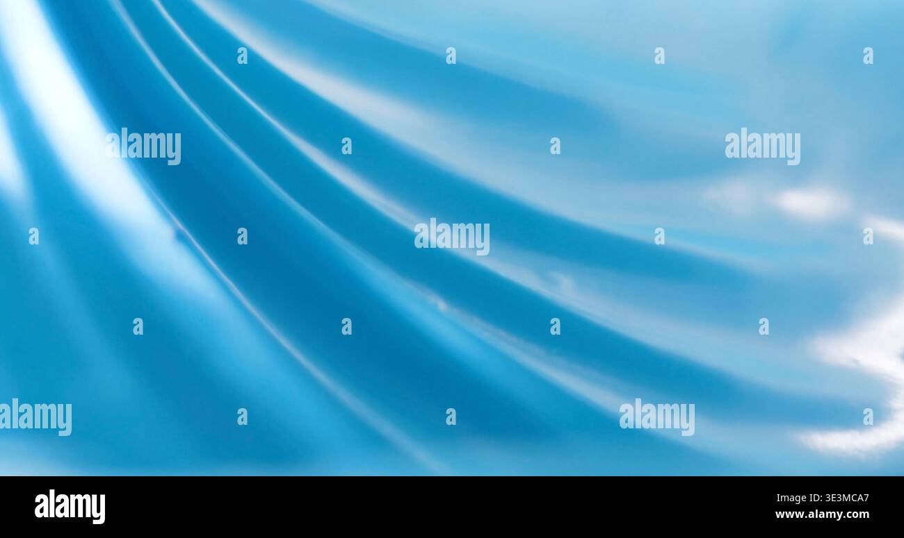 Bright blue fabric with smooth texture and soft folds under light in indoor setting Stock Photo