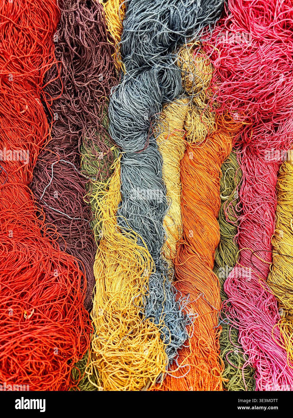 Skeins of silk yarn threads are tangled together in a shop window. Stock Photo