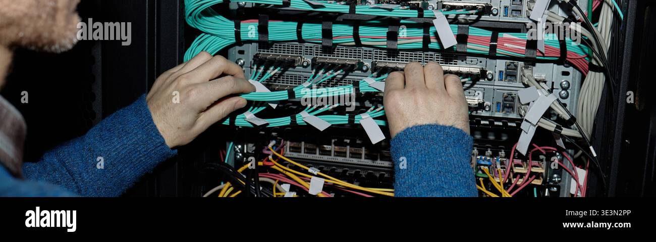 Man Configuring Network Cables in Server Rack Header Stock Photo