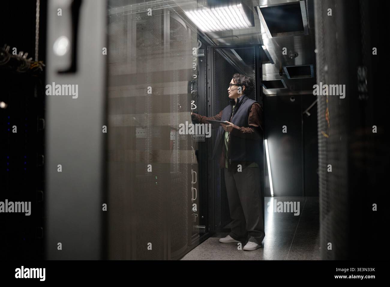 Young Adult Asian Man Troubleshooting Server Rack While Using Digital Tablet Stock Photo