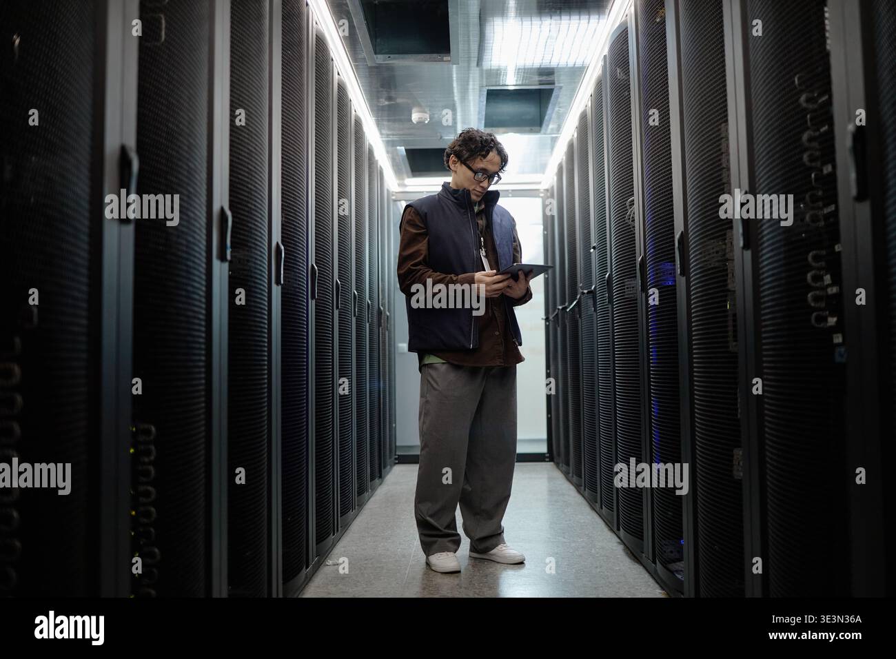 Young Adult Asian Man Using Digital Tablet While Working in Data Center Stock Photo