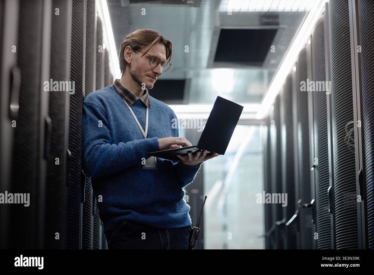 Caucasian Middle Aged Man Using Laptop While Working in Data Center Corridor Stock Photo