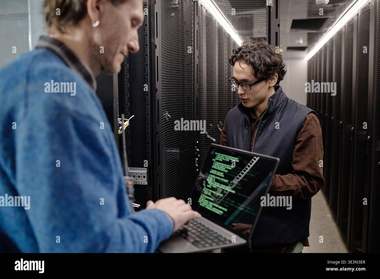 Men Collaborating with Laptop in Data Center Server Room Stock Photo
