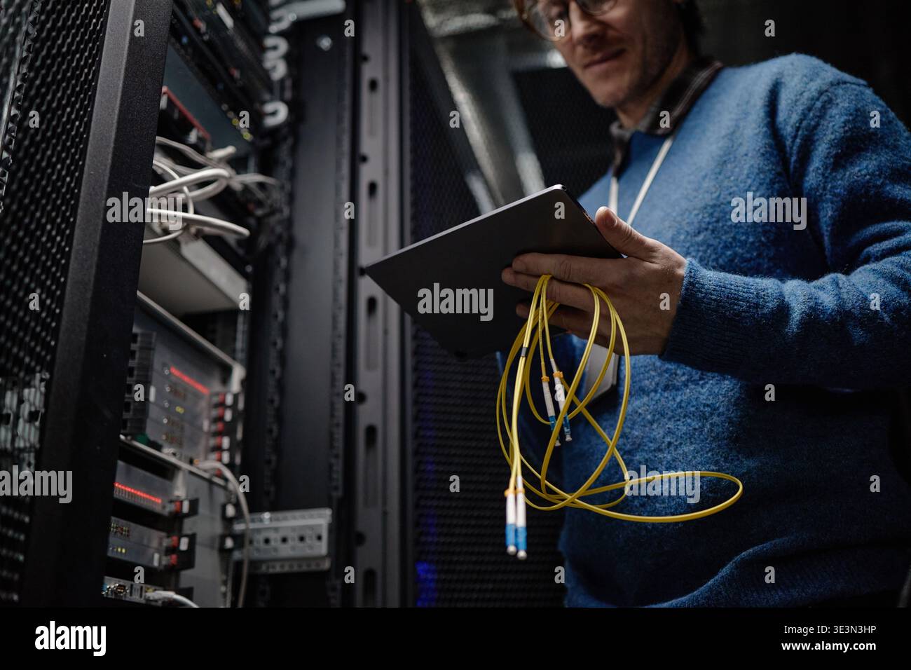Middle Aged Caucasian Man Inspecting Server Rack While Holding Tablet Device Stock Photo