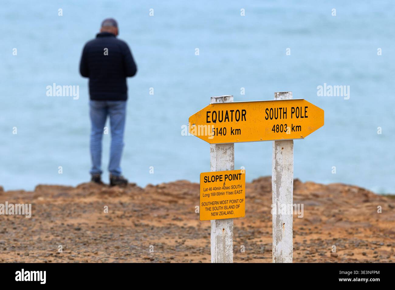 Visitor at Slope Point signpost showing distances to the Equator and ...