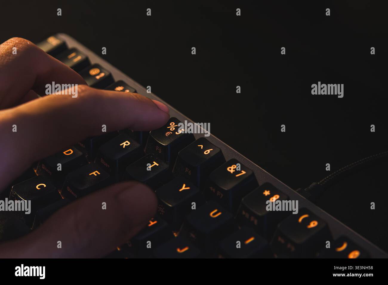 A detailed close-up shot of a person's index finger poised to press the percentage (%) symbol key on a mechanical computer keyboard. Stock Photo