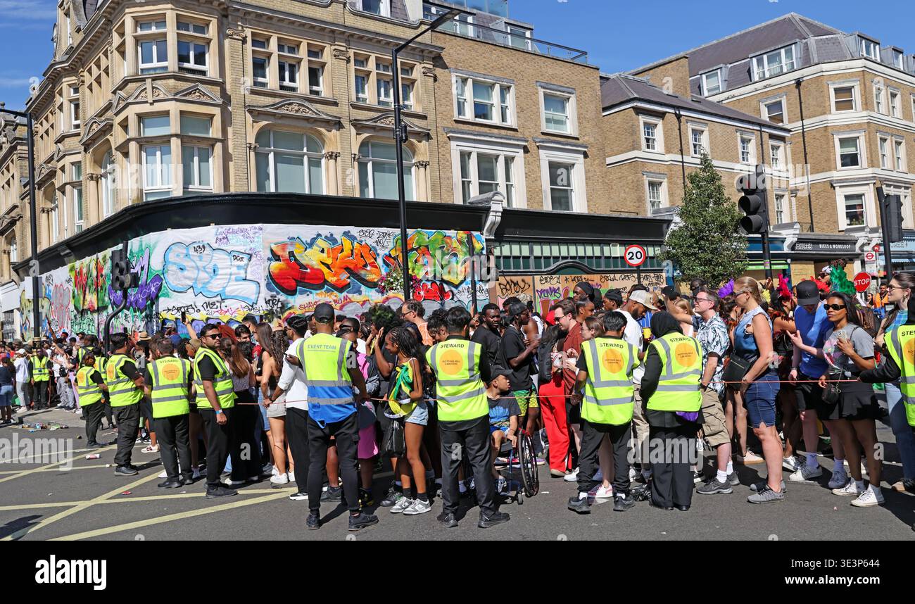 High-visibility stewards control Carnival crowds in west London as Notting Hill Carnival prepares for its 60th anniversary in 2026. Stock Photo