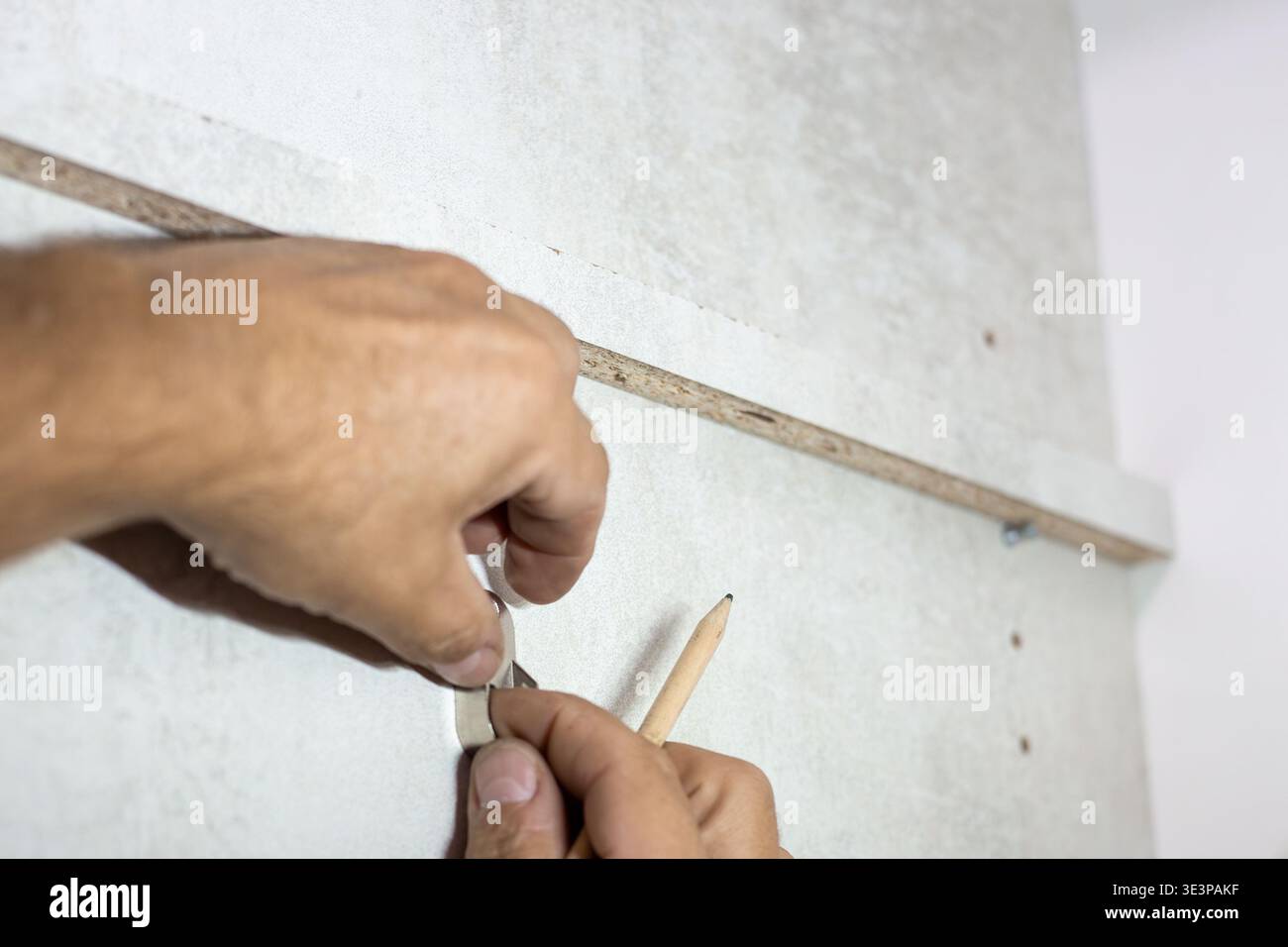 Worker's hands marking a wall with a pencil using a wooden guide Stock Photo