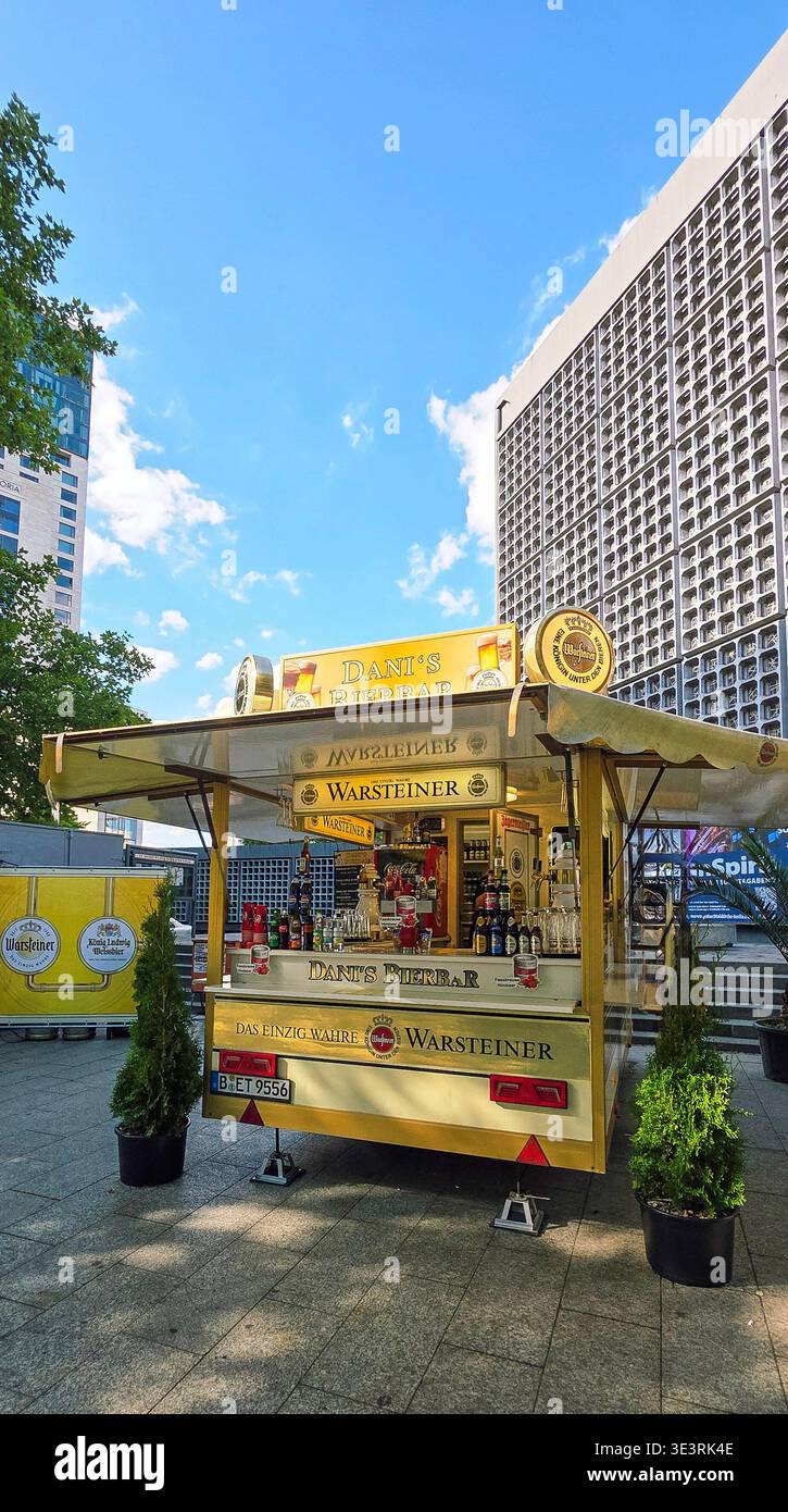 Berlin, Germany - August 18, 2025: Beer stand featuring Warsteiner branding in a vibrant urban environment with clear blue skies. - Smartphone Captured Stock Image
