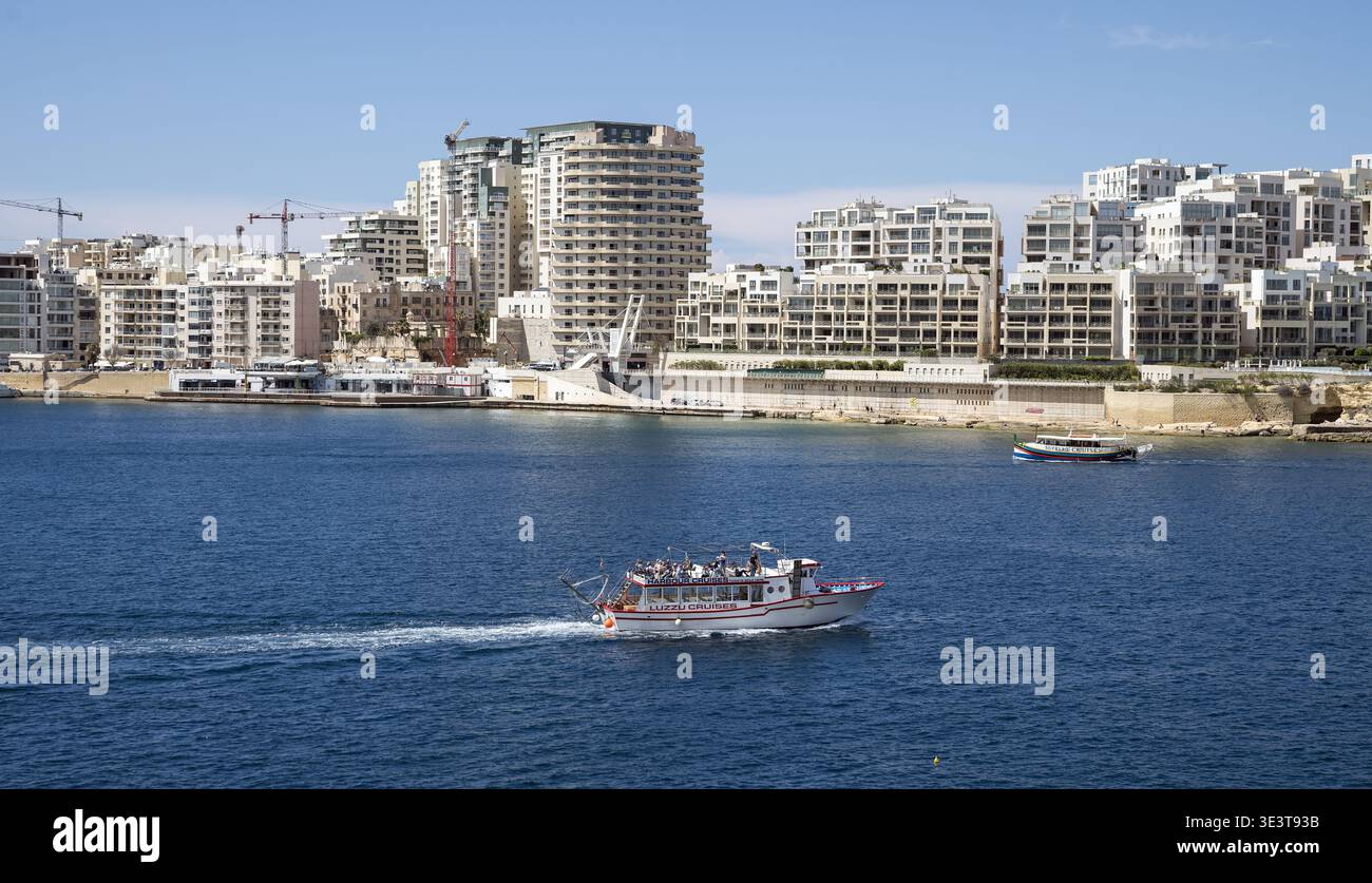 2019 Malta Valletta, a small cruise ship against the background of modern apartment blocks; Kreuzfahrtschiff vor dem Hintergrund moderner Wohnblocks Stock Photo