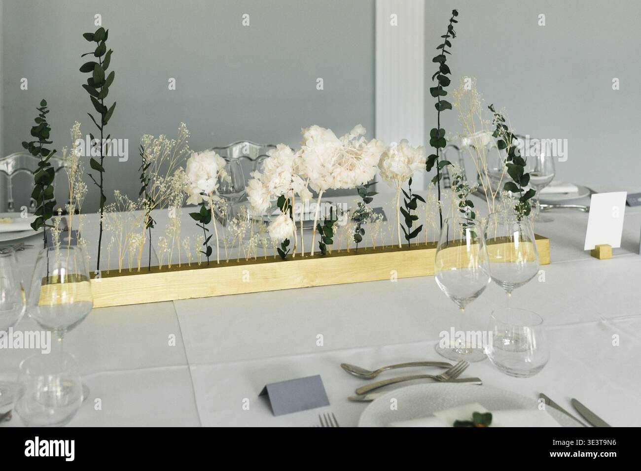Long minimalist centerpiece with eucalyptus and white flowers on table ...