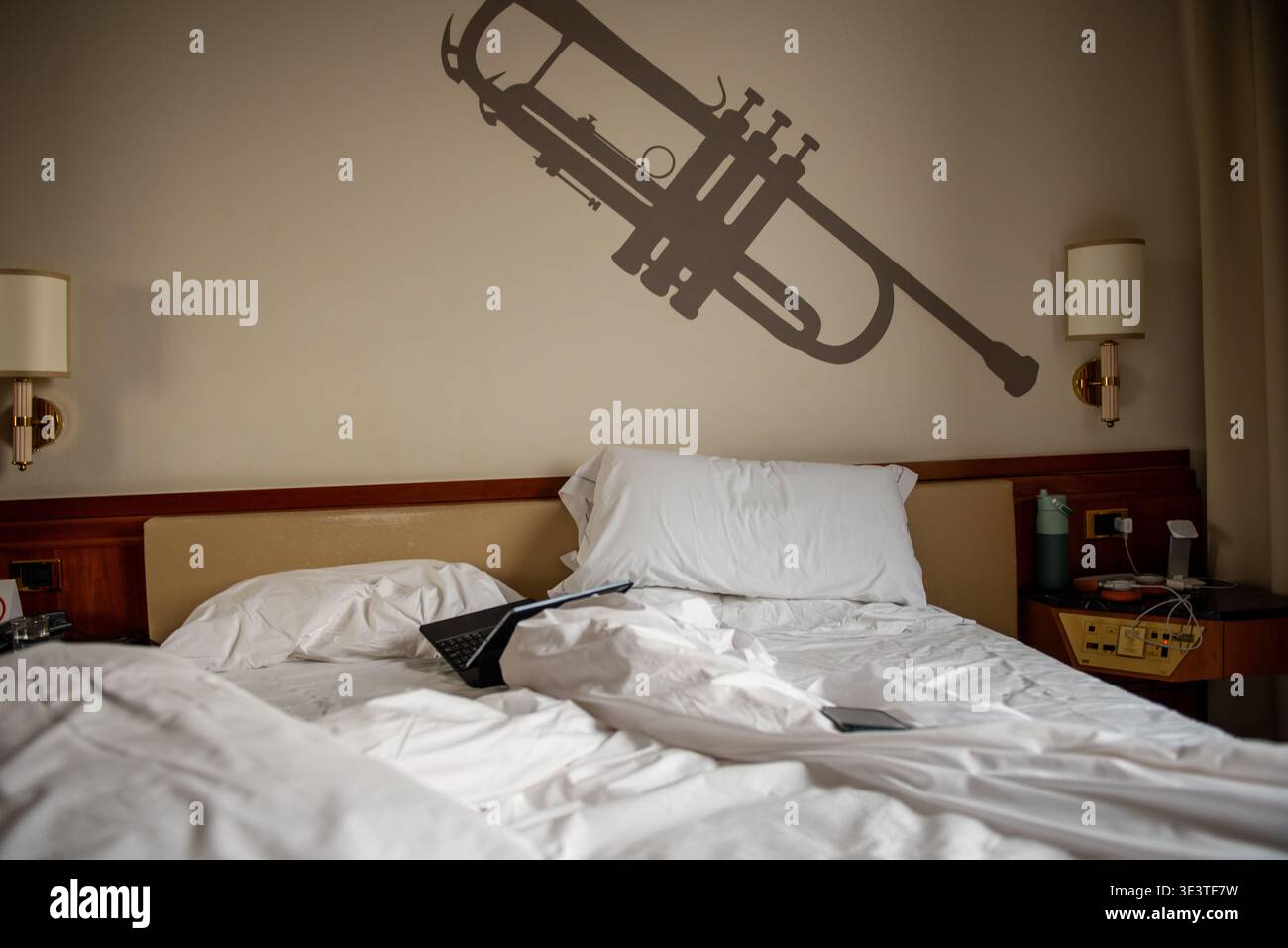 Unmade hotel bed with notebook computer on top Stock Photo