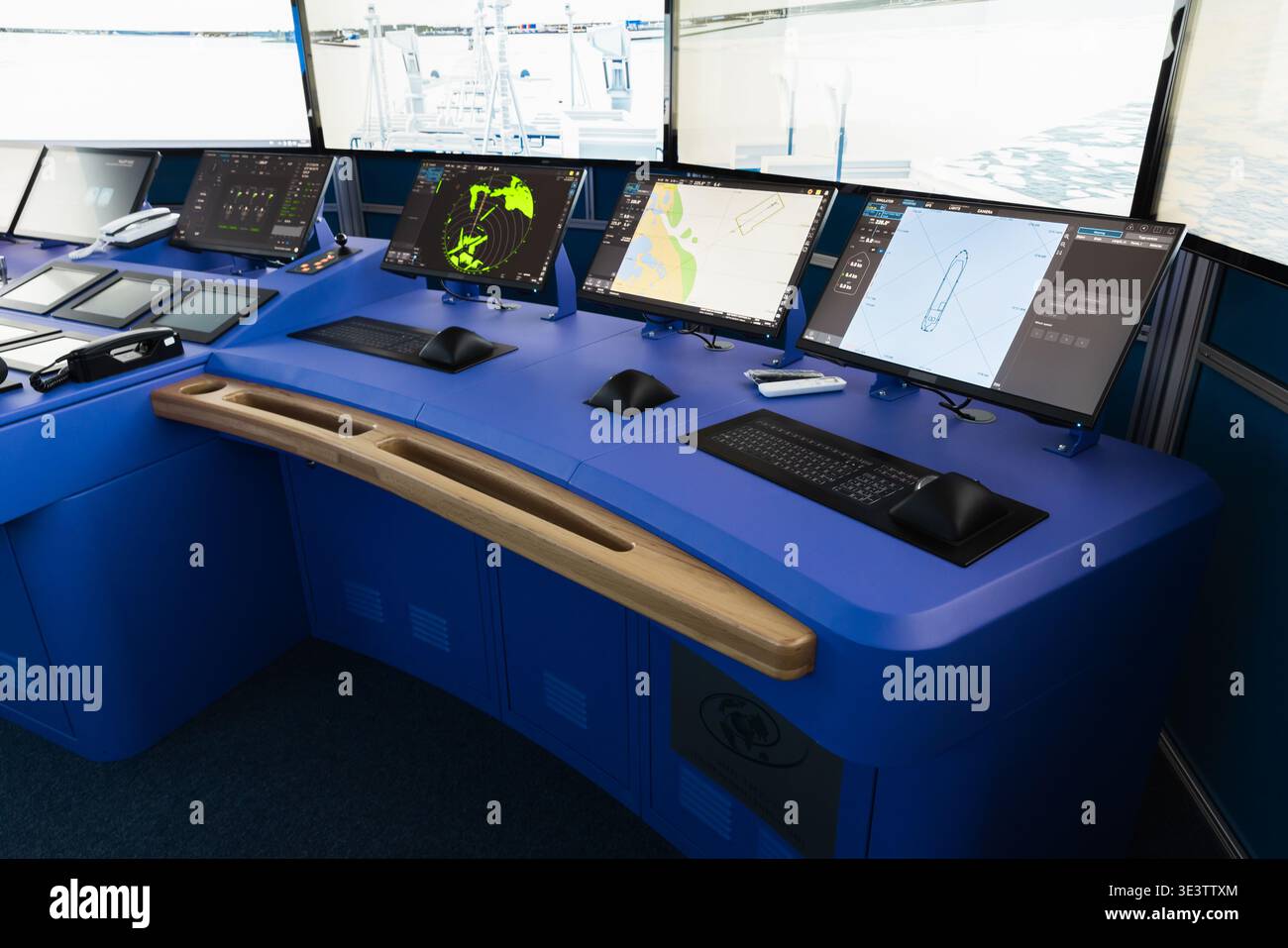 A modern ship bridge featuring a blue navigation console with multiple ...