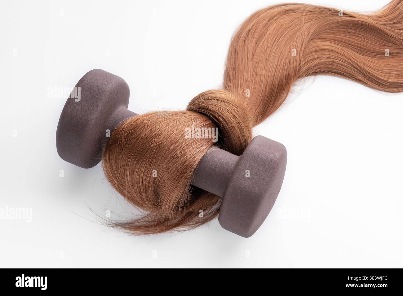 A unique concept image depicting strong, silky hair intertwined with a weight, symbolizing the strength and vitality achieved through hair cosmetics a Stock Photo
