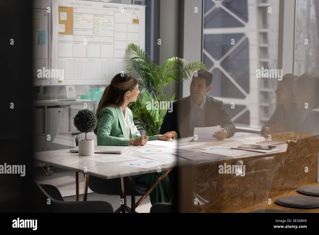 Female project manager discussing documents with diverse associates around table Stock Photo