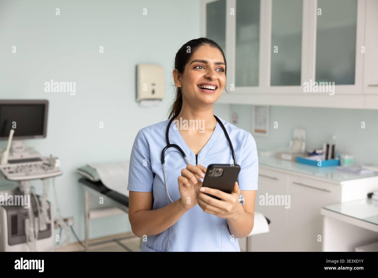 Smiling female Indian nurse using her smart phone Stock Photo