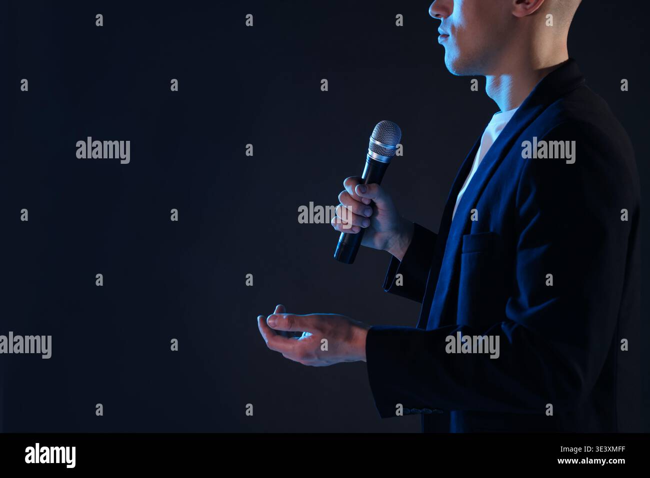 Presenter with microphone performing on dark background, closeup. Space for text Stock Photo