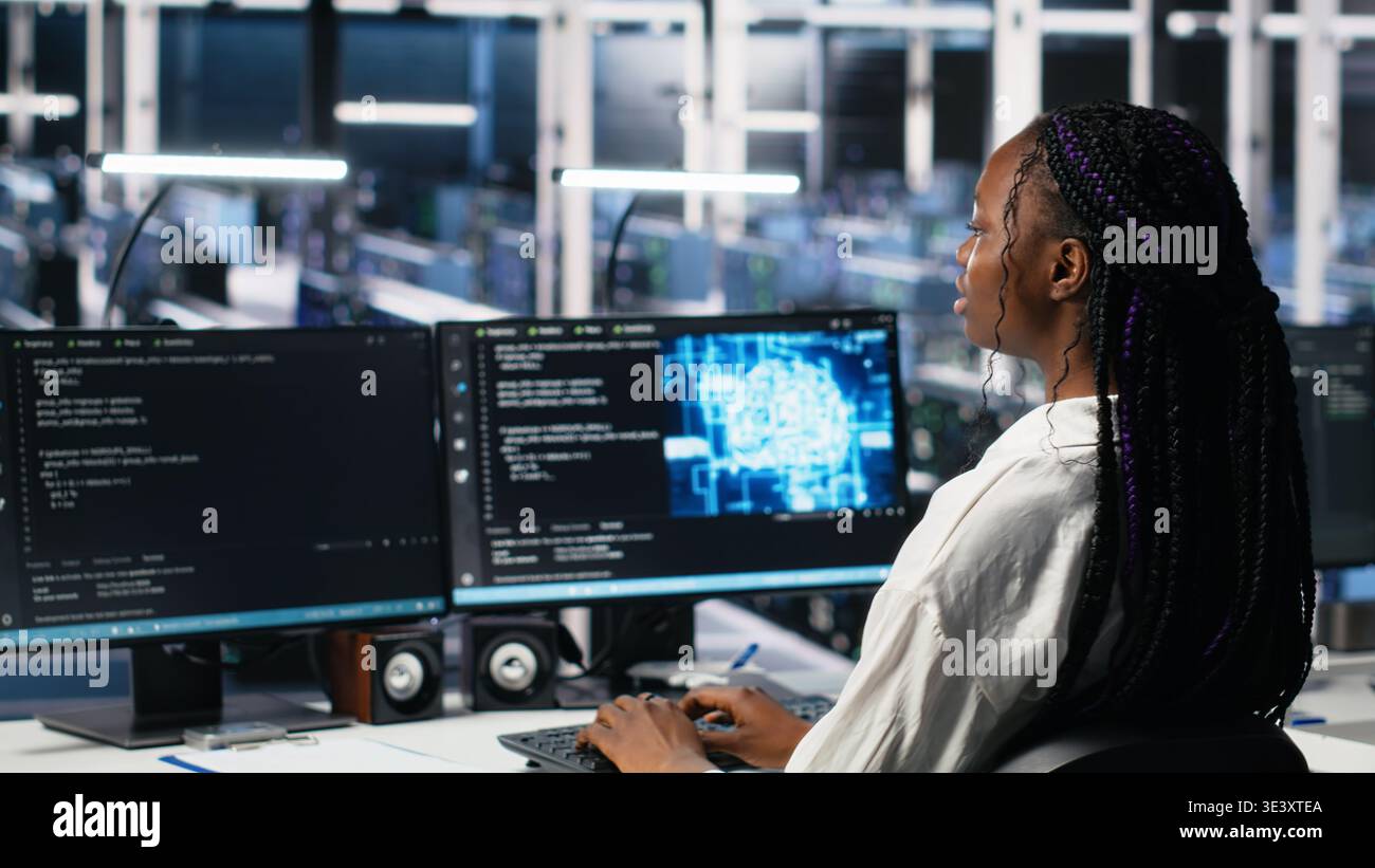 Female programmer in data center reviews AI diagnostics, analyzing neural network performance. Server hub IT expert optimizes artificial intelligence systems configuration, camera A Stock Photo