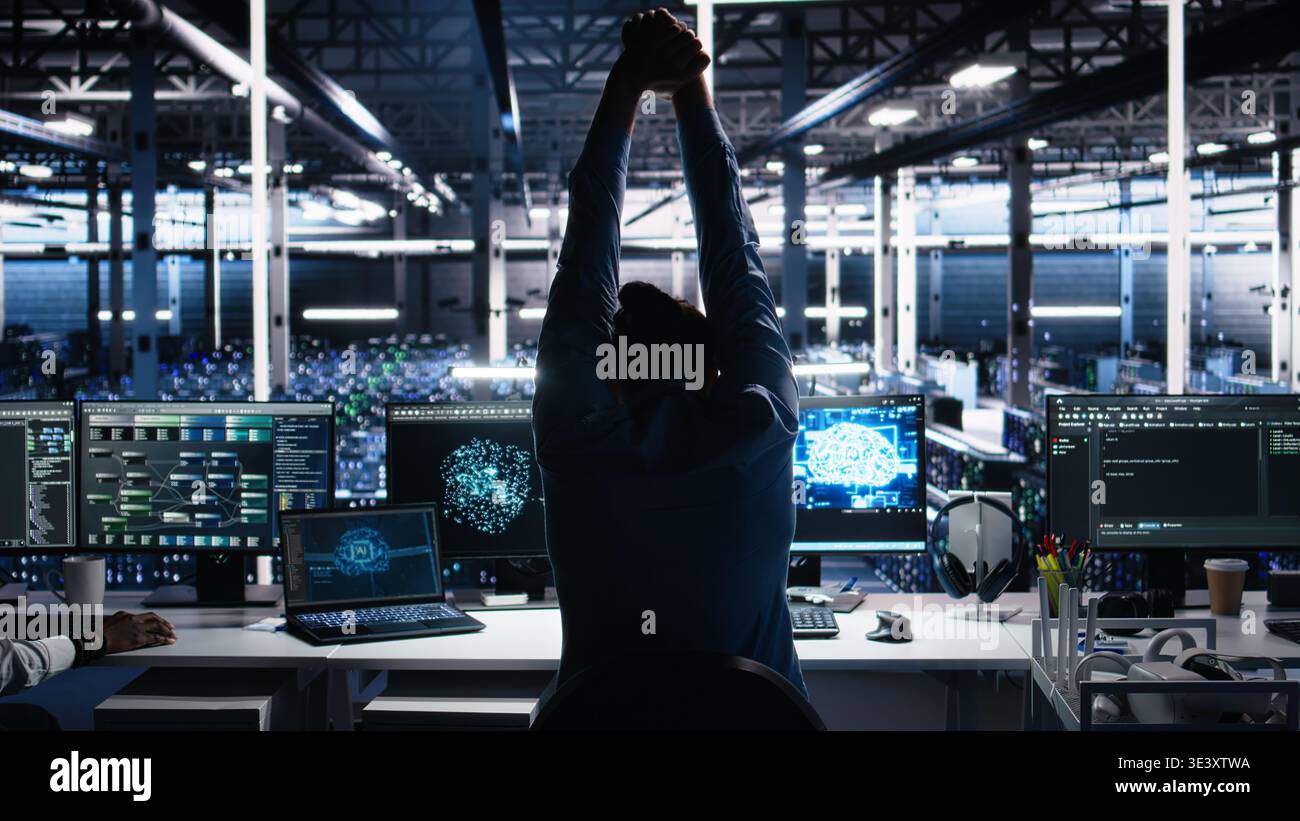 Server room technician stretching sore back while using AI at desk. Fatigued IT expert in data center relaxing strained muscles, feeling backache while using artificial intelligence, camera A Stock Photo