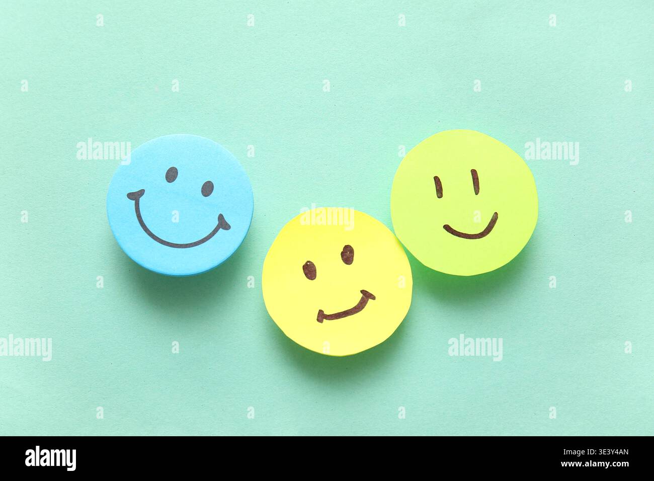 Sticky notes with smiley faces on turquoise background Stock Photo