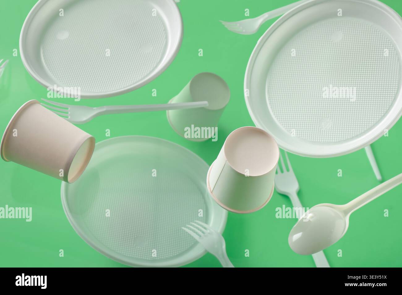 White plastic tableware levitating on green background Stock Photo
