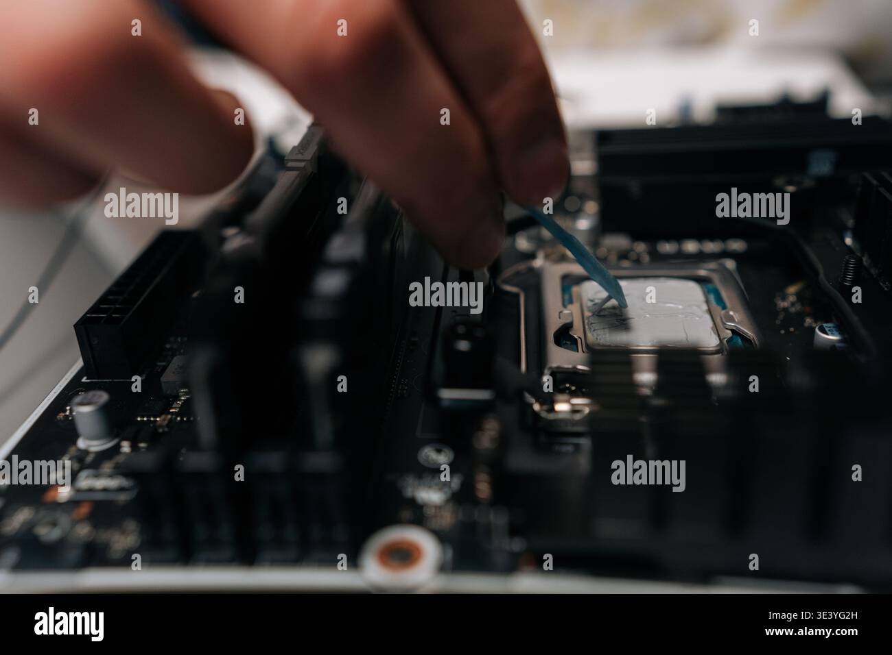 Close-up hands of unrecognizable technician applying thermal paste on computer processor, spreading precise layer for efficient cooling and improved Stock Photo