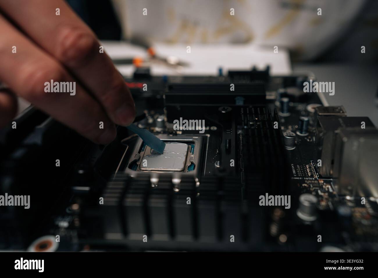 Technician applying thermal paste on computer processor, spreading precise layer for efficient cooling and improved performance during hardware Stock Photo
