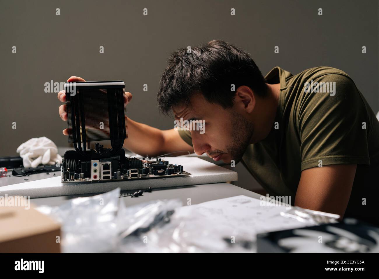 Concentrated computer technician carefully installing CPU cooler onto motherboard, performing maintenance and upgrade service on desktop computer Stock Photo